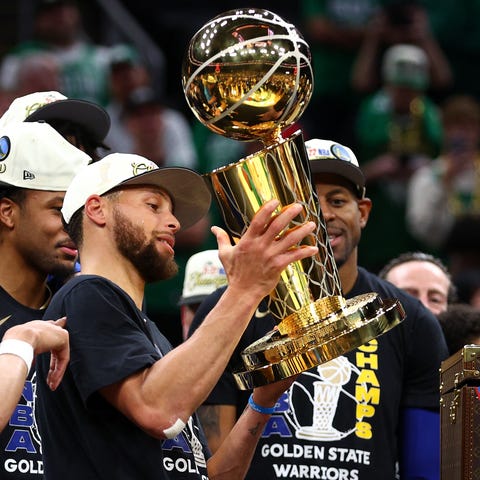 Steph Curry raises the Larry O'Brien Trophy.