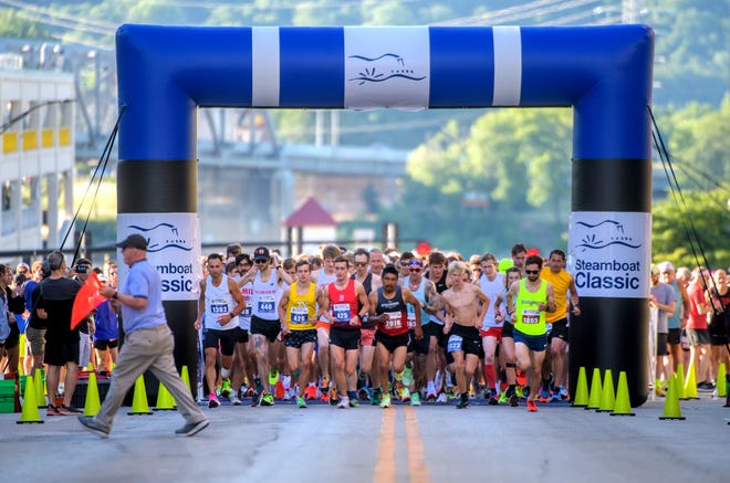 Steamboat Classic starter Stu Regnier, left, runs out of the way as runners bolt from the starting line of the 48th running of the Steamboat Classic 1-mile, 4-mile and 15K races Saturday, June 18, 2022 in downtown Peoria.