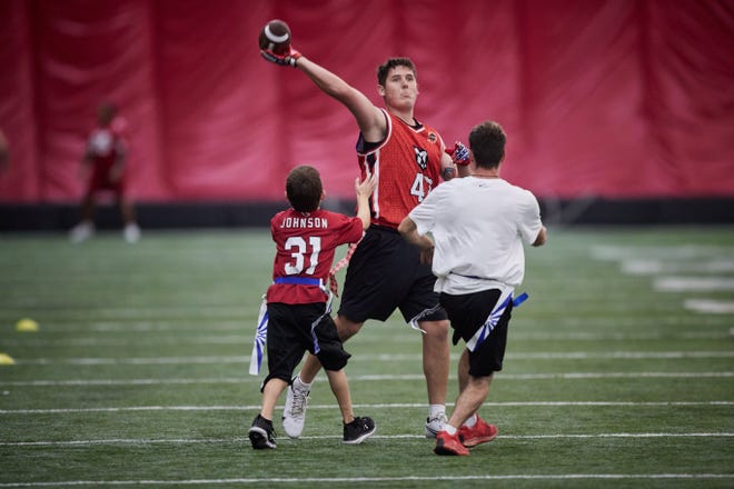 Jun 18, 2022;  Tempe, Arizona, USA;  Preston Pappas, 19, looks to pass the ball while being pressured by Brandon Fischer, 14, and Kyle Lewis, 20, in a scrimmage during a youth football camp at the Cardinals' training facility.