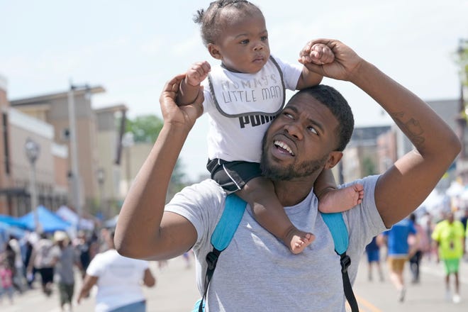 Demille Lowery carries his nearly 1-year-old son, Demian Lowery, on his shoulders during the Juneteenth Day celebration on Father's Day in Milwaukee on Sunday.