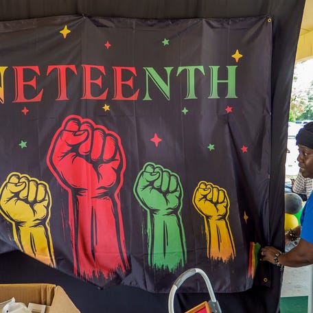 Tracey Brown arranges a banner at a Juneteenth celebration at Cauley Lott Park in Mount Dora, Fla. on Saturday, June 18, 2022. 