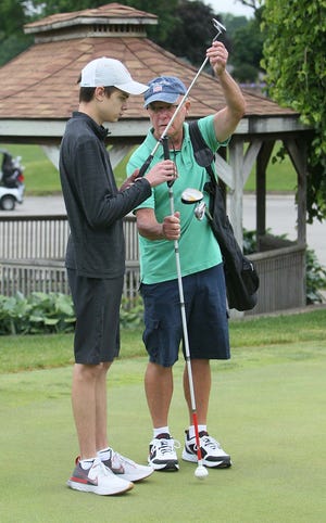 Huston Nagy, 16, left, of North Olmsted, swaps his white can for a putter from his grandfather Dave Szabo to use on the putting green at Firestone Country Club on Monday in Akron.