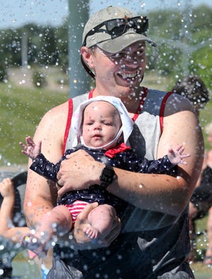 Trevor Burkett gra ze swoją sześciomiesięczną córką Joanną Burkett w Splash Pad w Veterans Park w Blaine Town. Na letnim wycieczce była też matka i babcia Joanny Ali Burkett, Janie Murphy.