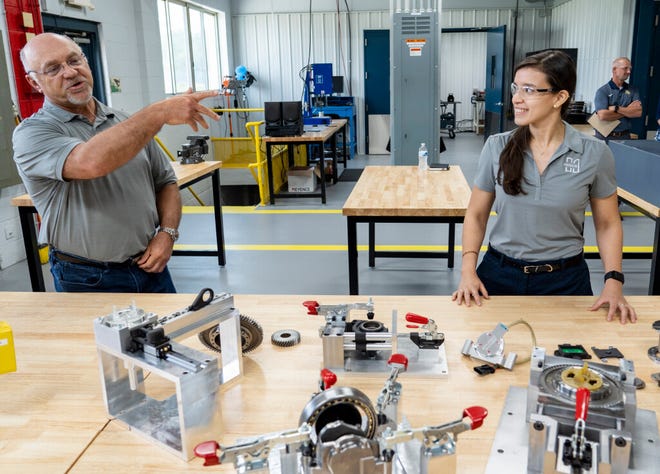 Todd Zakreski, president of HUSCO Automotive, and Nelsy Hernandez, program manager, showcase the new technology developed in the fabrication lab at HUSCO International Inc. to improve electric vehicle efficiency and extend battery range.