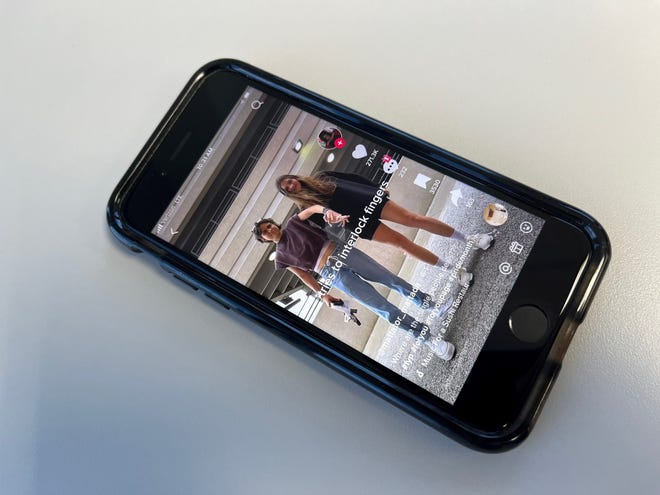 A photo of an iPhone displaying a TikTok video of  Makeala "Mak" and Mattea Ingemi.