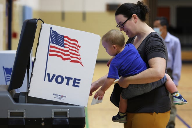 A voter casts her ballot with her child at a polling station at Rose Hill Elementary School during the midterm primary election on June 21, 2022 in Alexandria, Virginia.