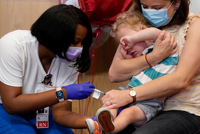 Leo Simon, 2, covers his eyes as registered nurse Reisa Lancaster administers a dose of a Pfizer COVID-19 vaccine at Children's National Hospital's research campus June 21 in Washington. Holding Leo is his mother, Brittany Head.