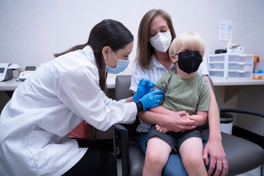 Pharmacist Kaitlin Harring, left, administers a Moderna COVID-19 vaccination to three year-old Fletcher Pack, while he sits on the lap of his mother, McKenzie Pack, at Walgreens pharmacy Monday, June 20, 2022, in Lexington, South Carolina.