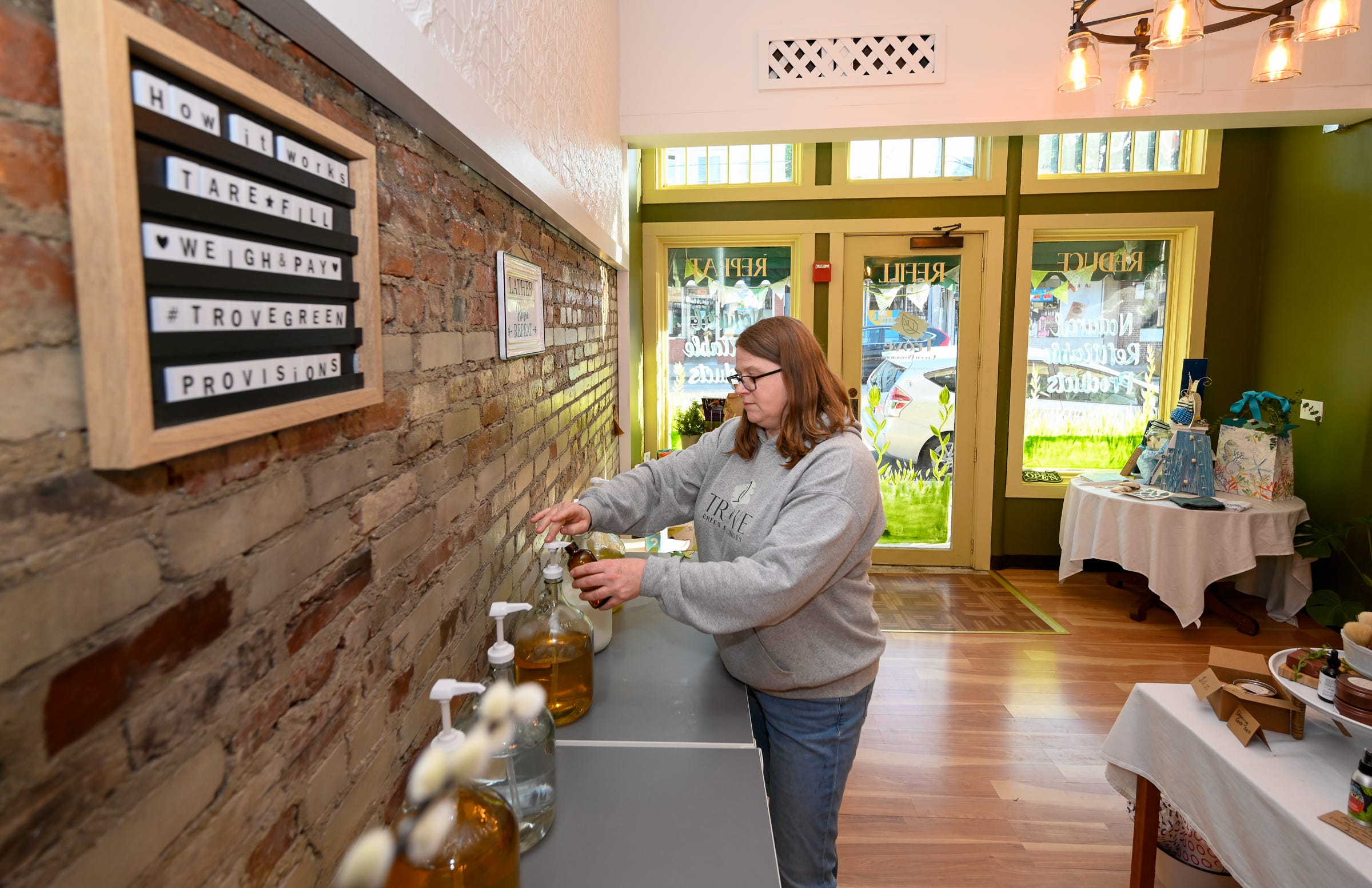 Clare Flaherty fills up a glass bottle of liquid soap at the refilling station at Trove Green Provisions in Medford on Tuesday, June 21, 2022.