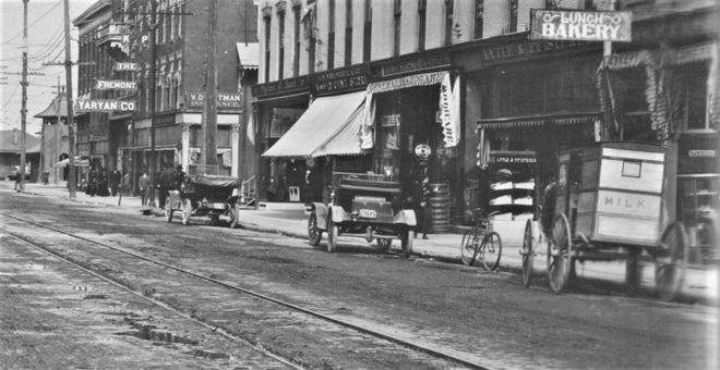Early autos and a milk wagon sit on Fremont's Front Street in about 1910.