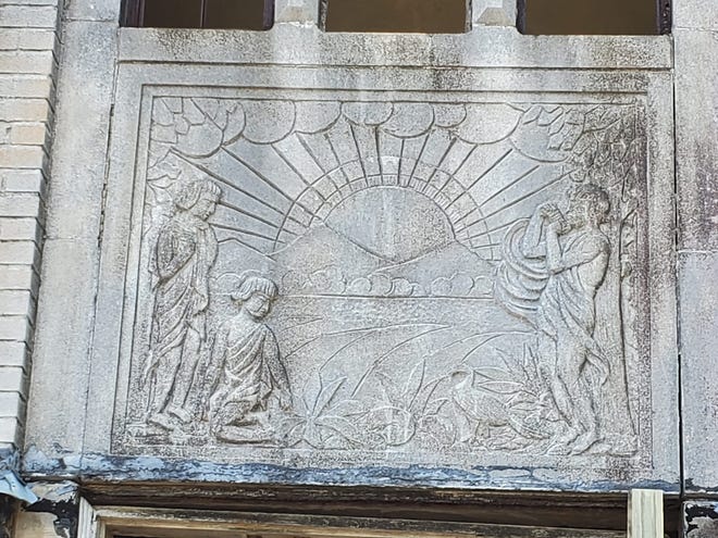 A decorative mural made from concrete adorns the building just above the front entrance.