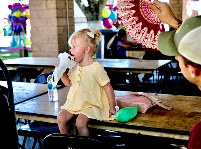 Maddy Reese, 2, of Cottonwood cools down with a frozen banana while getting fanned by her father, Daniel Reese, on a hot Wednesday afternoon during opening day of the Shasta District Fair on June 22, 2022.