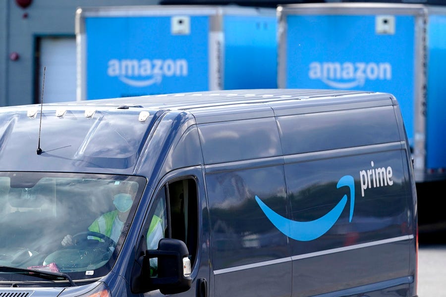 An Amazon Prime logo appears on the side of a delivery van as it departs an Amazon warehouse location in Dedham, Mass.