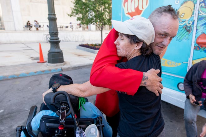 Former Detroit Red Wing Darren McCarty, right, hugs Laurie Oleska of Battle Creek, who traveled with her son, Dan, who uses a wheelchair to attend a rally for changes to no-fault automobile insurance reforms at the Spirit of Detroit Plaza, in Detroit.