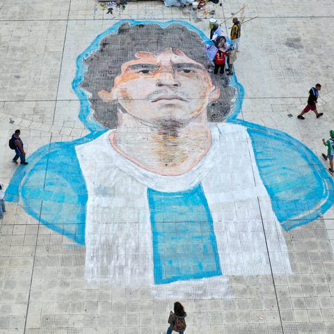 People walk past of the face of Diego Maradona pai