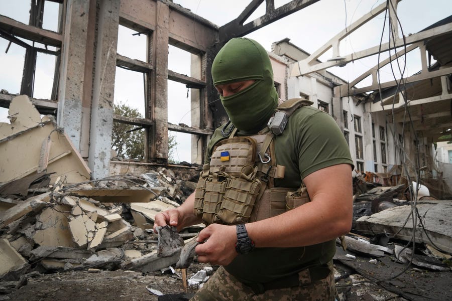 A Ukrainian serviceman holds rocket fragments at the ruins of the sports complex of the National Technical University in Kharkiv, Ukraine, Friday, June 24, 2022, damaged during a night of shelling. The building received significant damage. A fire broke out in one part but firefighters managed to put it out.