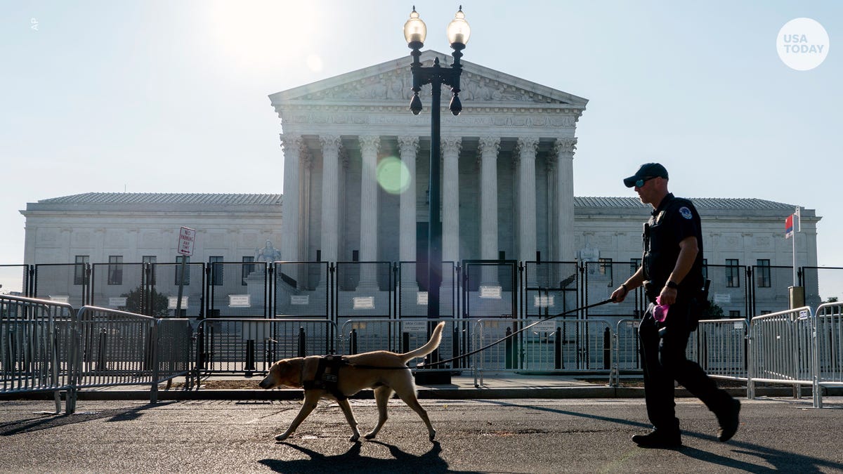 A police officer leads a K9 around steel fencing and barricades surrounding the Supreme Court, Friday, June 24, 2022, in Washington. The Supreme Court has ended constitutional protections for abortion that had been in place nearly 50 years in a decision by its conservative majority to overturn Roe v. Wade. (AP Photo/Gemunu Amarasinghe)