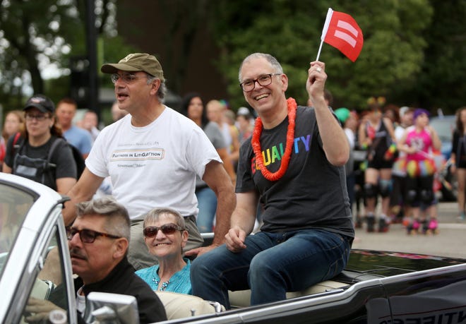 Jim Obergefell holds up an equality flag while riding in the Cincinnati Pride Parade with his attorney, Al Gerhardstein, and Paulette Roberts, aunt of his late husband, John Arthur, on June 27, 2015. Obergefell is the named plaintiff in the Obergefell v. Hodges Supreme Court case that legalized same-sex marriage nationwide.