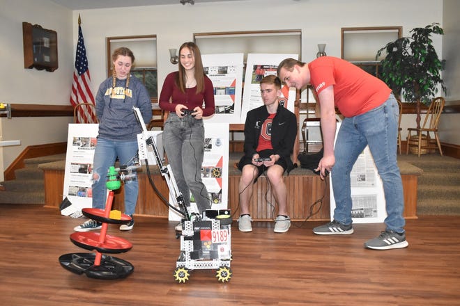 Orion High School’s robotics team, All Charged Up, demonstrates the abilities of their robot, Steve 2.0, at Cambridge Public Library on Friday, April 15. From left, Maddie Greenwood watches Kaitlyn Greenwood, Eric Thorndyke and captain Colin Essary drive Steve 2.0 as he puts a green object on top of a tower.
