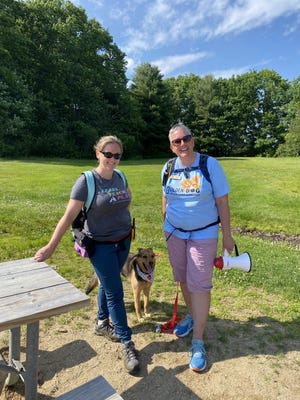 Laura Gendron, left, founder of Miss Behavior, a dog training serivce, and Traci Bisson, founder of Golden Dog Adventure Co., stand with Bisson's dog Gilley at Wagon Hill Farm in Durham during a Golden Dog event held June 12, 2022.