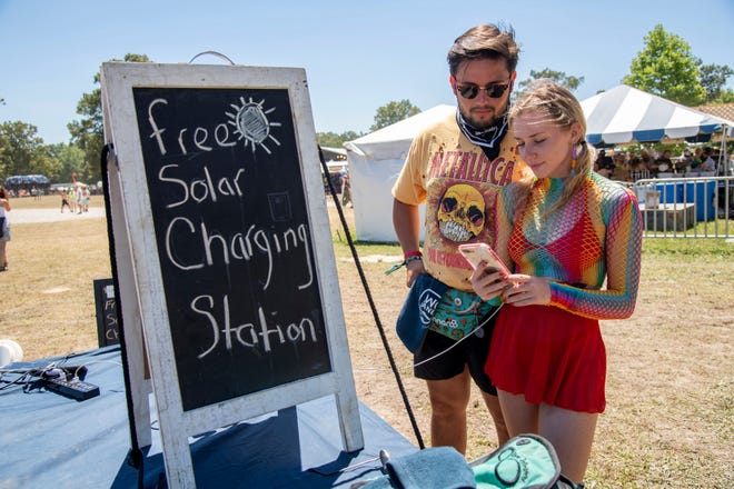 Festivalgoers use the free solar charging station at the Bonnaroo Music and Arts Festival on Saturday, June 18, 2022, in Manchester, Tenn.