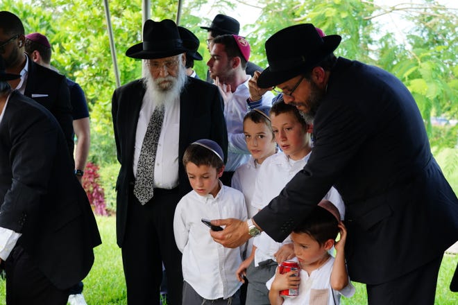 Rabbi Schneur Z Oirechman conducts the burial service for the Chabad scrolls as Rabbi Shalom B Lipskar looks on in Miami on June 19, 2022.
