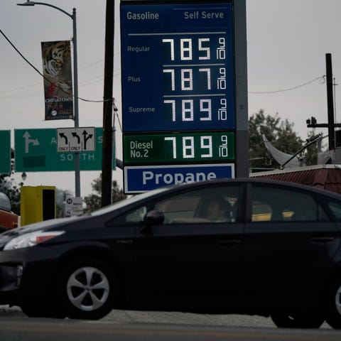 A price board is shown as a driver exits a gas sta