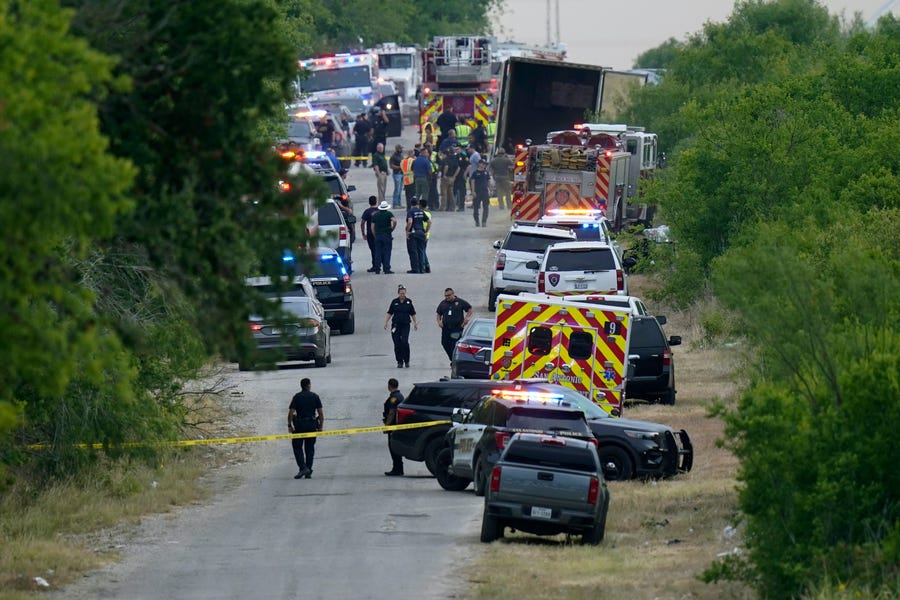 Police work the scene where dozens of people were found dead in a semitrailer in a remote area in southwestern San Antonio.
