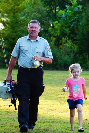 Michael Johnson, manager of the Green River and Clarks River national wildlife refuges in Western Kentucky, walks with one of his granddaughters, Maddy Johnson, at a Family Fishing Night event at the Clarks River Refuge in 2019.