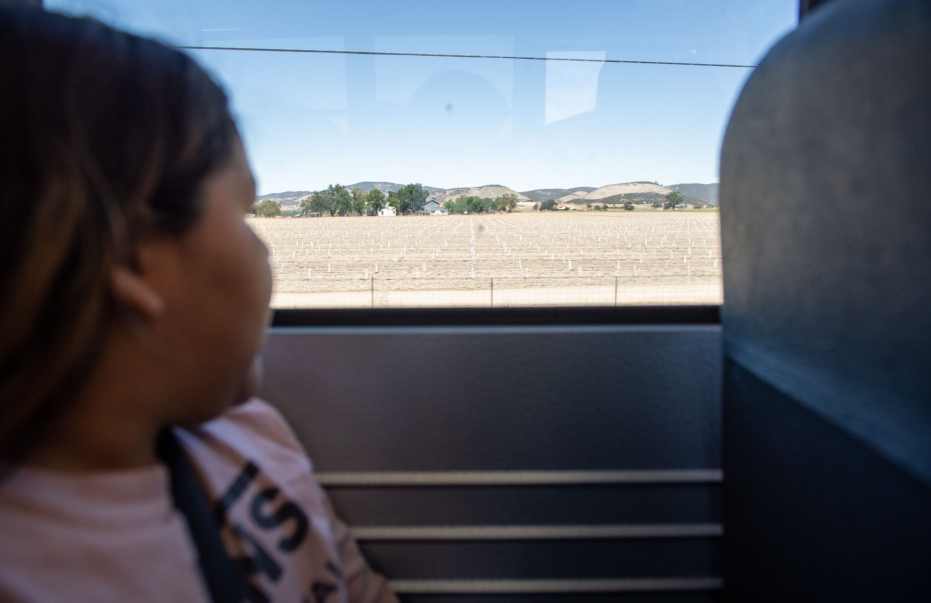 Irma Segura, 8, looks out the window of a school bus at dirt fields at the end of the school day at San Antonio Elementary School.