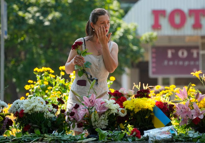 A woman lays flowers for the victims of the Russian rocket attack at a shopping center in Kremenchuk, Ukraine, Wednesday, June 29, 2022.