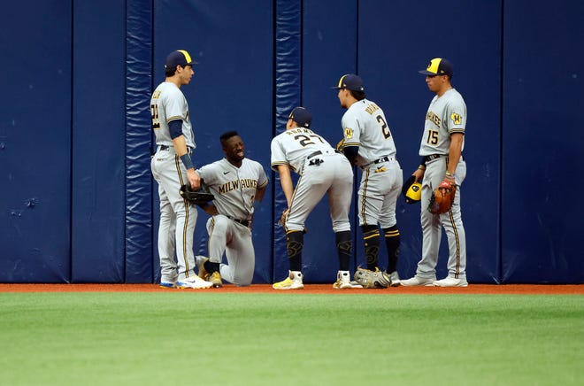 Brewers players check on centerfielder Jonathan Davis after he crashed head-first into the outfield wall while making a diving catch against the Rays on Wednesday.
