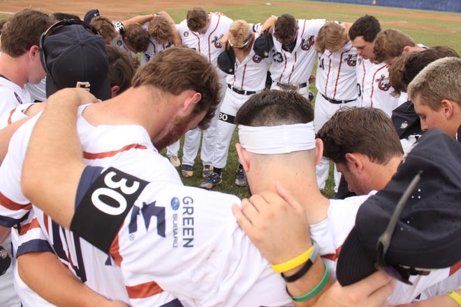 The Springfield Lucky Horseshoes huddle for a prayer prior to a home game against Clinton at Robin Roberts Stadium on Friday, July 1. It was Springfield's first game after one of its players, Lucas Otto, was killed in a car crash on Thursday.
