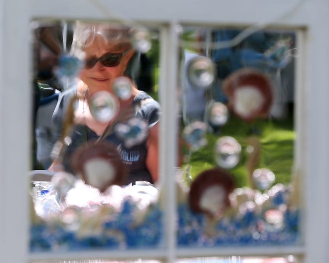 A woman is framed by a window decorated with found seashells at a booth for Seashells by Paul in Marshfield during the 128th Summer Blessings Fair at First Congregational Church of Marshfield on Saturday, July 2, 2022.