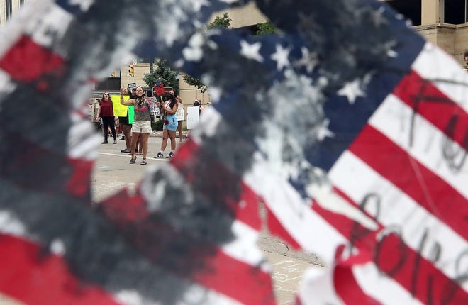 Lunedì i manifestanti sono raffigurati mentre tengono una bandiera americana strappata fuori dall'Harold K. Stubbs Justice Center.