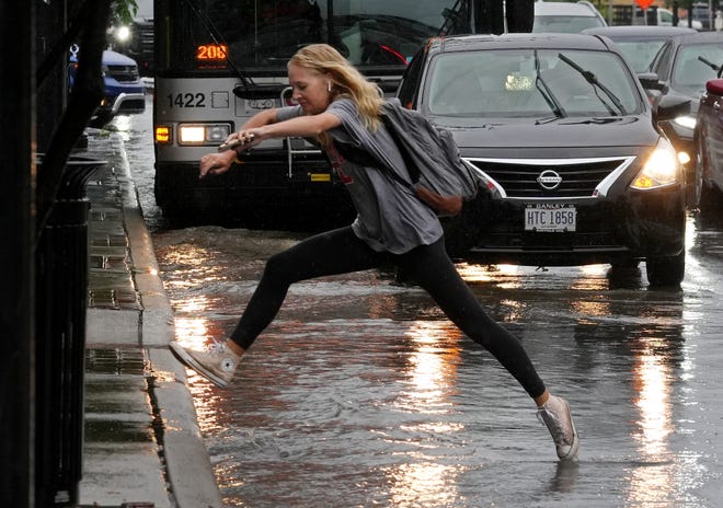 An Ohio State University student leaps over a puddle on a rainy day in July. Warm temperatures and rain were back in central Ohio Tuesday, despite the fact that it was January.