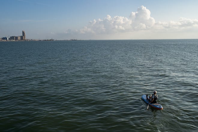 Ken Johnson paddles an inflatable paddle board at Cole Park as the Corpus Christi, Texas, skyline rises in the distance on Wednesday, July 6, 2022.