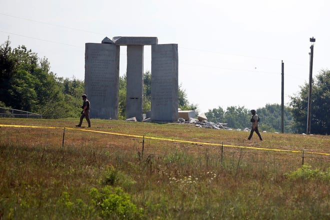 Law enforcement officials walk around the damaged Georgia Guidestones monument near Elberton, Ga., on Wednesday, July 6, 2022. The Georgia Bureau of Investigation said the monument, which some Christians regard as satanic, was damaged by an explosion before dawn.