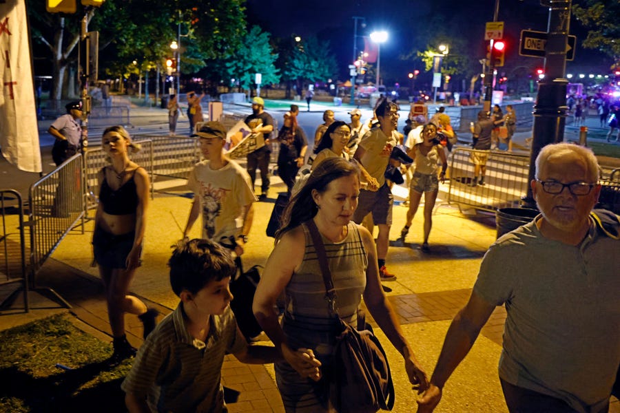 People hurry off the Parkway after two police officers were struck by bullets during the July 4th fireworks show on the Benjamin Franklin Parkway in Philadelphia on Monday, July 4, 2022.