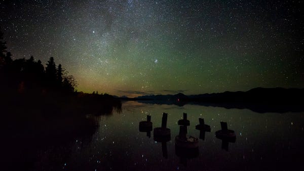 A starry night sky is reflected upon Lake Clark.