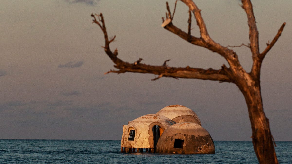 Waves lap on the sides of the dome homes on Cape Romano in Collier County, Florida, in late June 2022. The homes were built on the beach on dry land in the early 1980s. Without ever moving, they now find themselves several hundred feet offshore. Erosion, hurricanes and strong tropical weather have contributed to the demise of the homes. Climate change is causing sea-level rise. Planners say that the homes should have never been built in this location due the changing landscape of barrier islands.