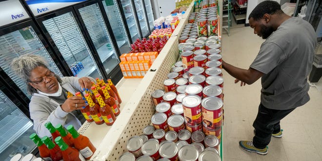 Yvette Watkins, left, and Chaleb Scruggs stock shelves inside of Sherman Park Grocery.