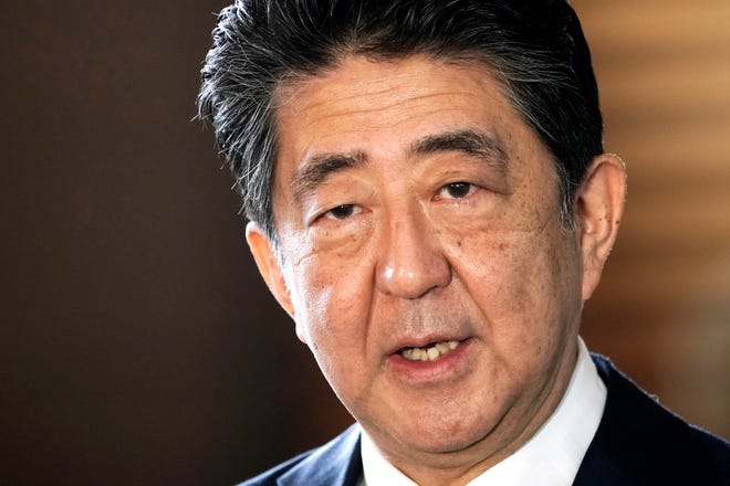 Japan’s former Prime Minister Shinzo Abe is pictured speaking to the media as he arrives at the prime minister's office for a cabinet meeting in Tokyo.