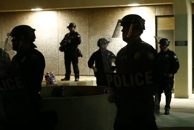 FILE - Phoenix Police stand in front of police headquarters on May 30, 2020, in Phoenix, waiting for protesters marching to protest the death of George Floyd. Arizona's governor has signed into law a measure that makes it illegal to knowingly record video of police officers within 8 feet (2.5 meters) or closer without an officer's permission, spurring concerns among civil rights activists about transparency and accountability. (AP Photo/Ross D. Franklin, File)