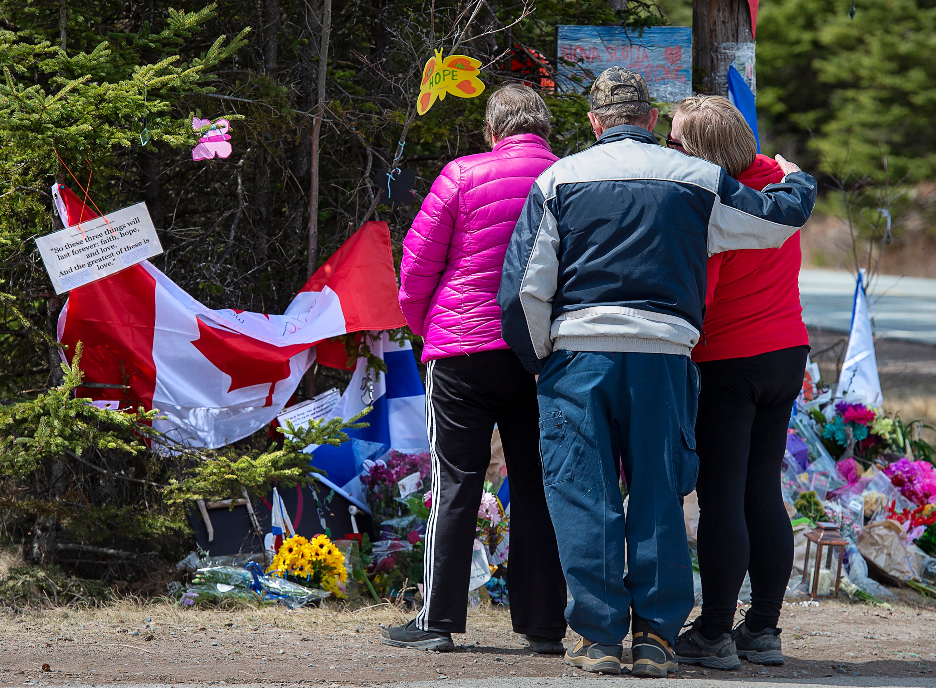 A family pays their respects to victims of the mass killings at a checkpoint on Portapique Road in Portapique, Nova Scotia, on Friday, April 24, 2020. A man, wearing a police uniform and driving a mock-up cruiser, killed 22 people in a murder rampage in Portapique and several other Nova Scotia communities.