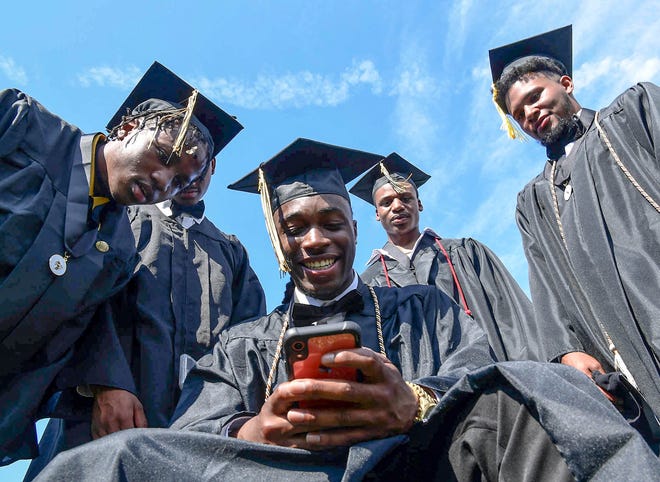 Shy'heem Clemons looks at his phone photos with friends before the T.L. Hanna High School commencement in Anderson, June 4, 2020.