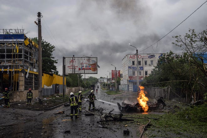 Petugas penyelamat memadamkan api dari mobil yang hancur setelah serangan Rusia di lingkungan perumahan di pusat kota Kharkiv, Ukraina, pada Senin, 11 Juli 2022.