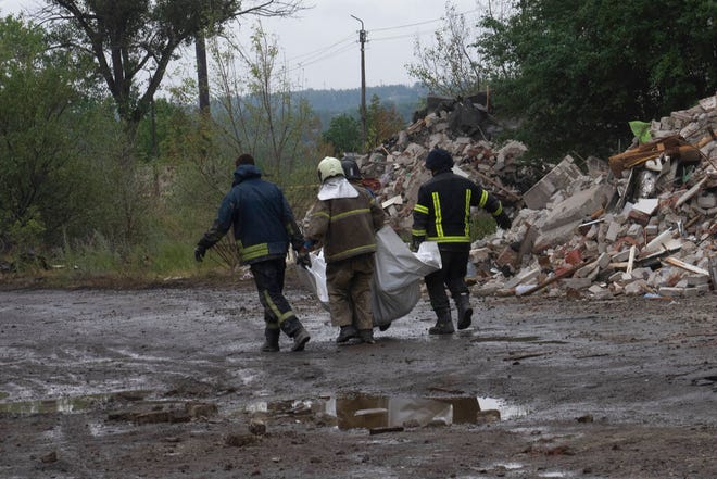 Pekerja darurat Ukraina membawa mayat korban yang ditemukan di bawah puing-puing setelah serangan roket Rusia menabrak gedung apartemen Sabtu malam, di Chasiv Yar, wilayah Donetsk, Ukraina timur, Senin, 11 Juli 2022.