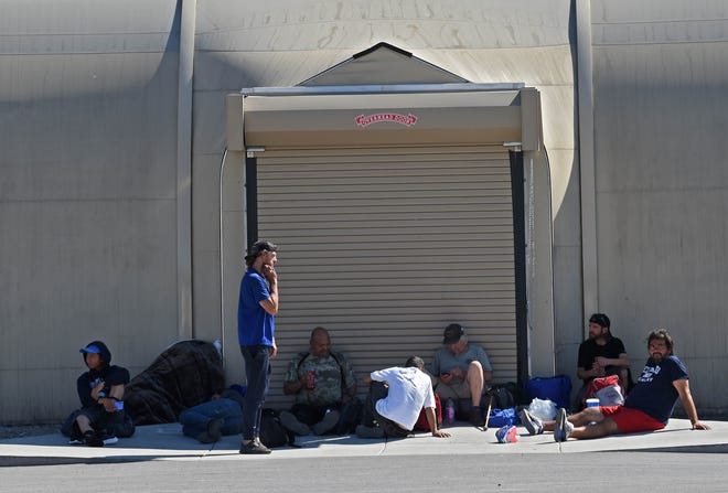 Homeless staying at the Cares Campus shelter wait outside the shelter during a routine cleaning of the facility on July 11, 2021. 