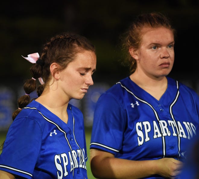 Collins-Maxwell's Avery Fricke (left) fights back tears as the Spartans huddle together one last time following a 4-2 loss to Newman Catholic (Mason City) in the 1A regional softball final at Collins Monday.